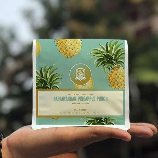 a hand holding a card with pineapples in the background.