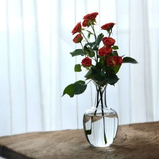 a vase with red roses in it on a table.