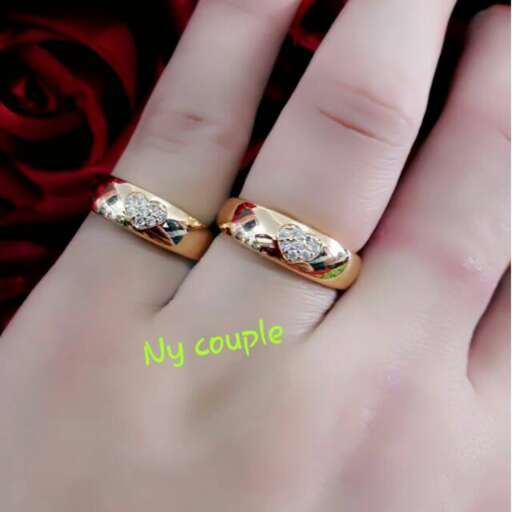 a couple of gold rings with a red rose and white diamond.