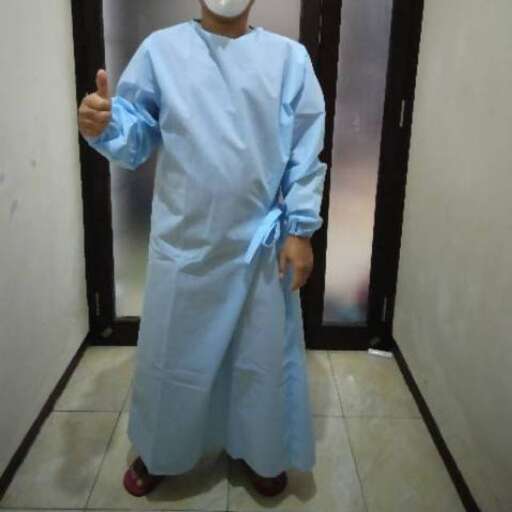 a man in a surgical mask standing in a room.