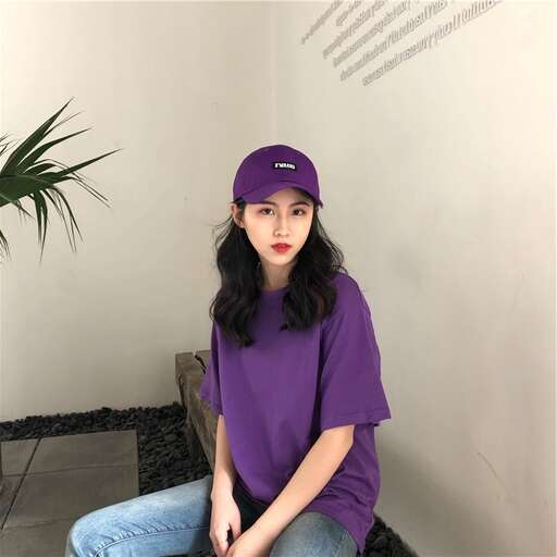 a girl in a purple baseball cap sitting on a chair.