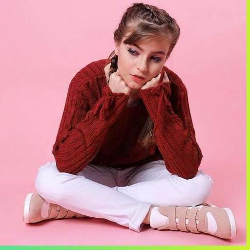 a girl in a red sweater sitting on the ground.
