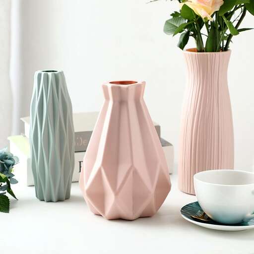a pink vase with a flower in it.