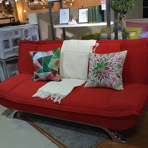 a red couch with pillows on it in a room.