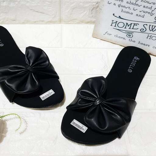 a pair of black slippers with a sign saying 
