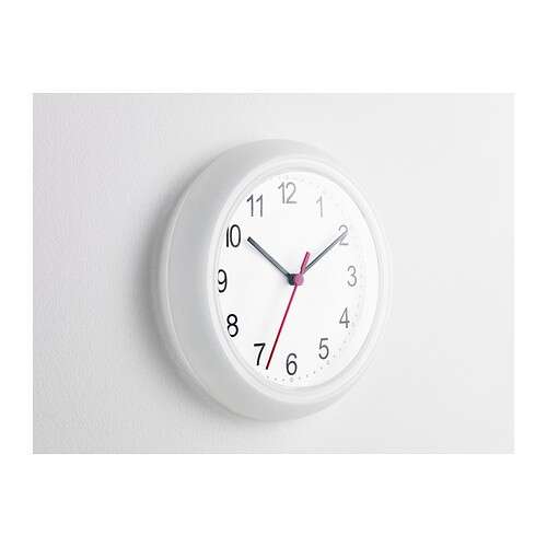 a clock hanging on a wall with a white wall background.
