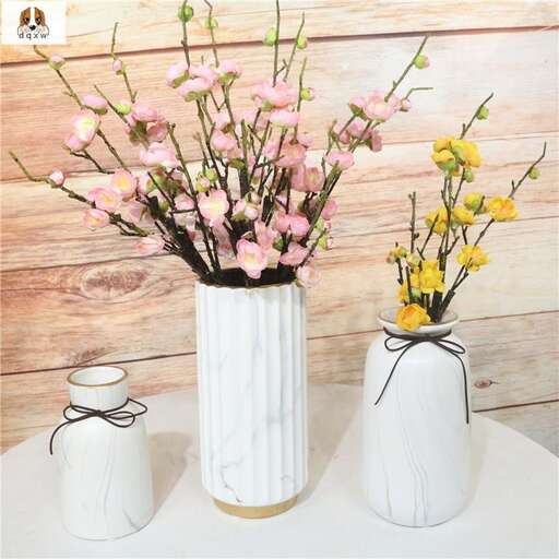 a white vase with pink flowers in it.