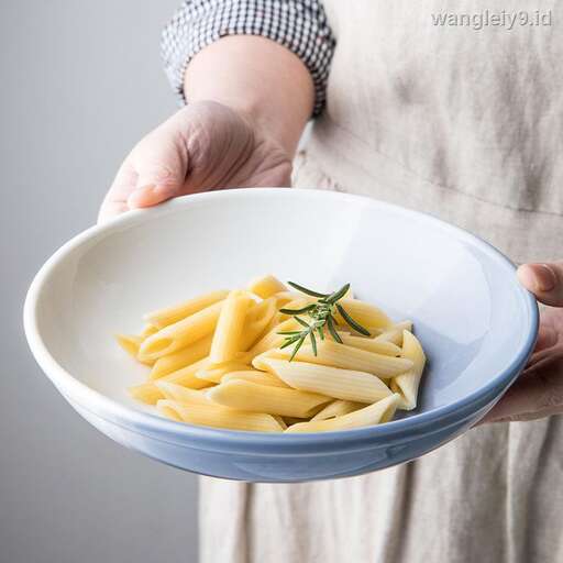 a person holding a bowl of pasta.