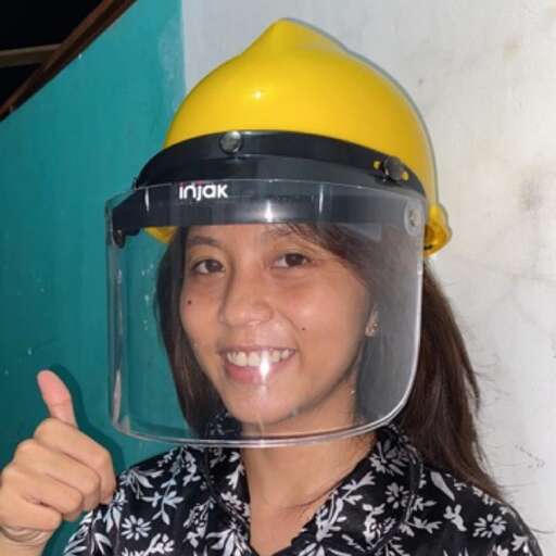 a girl in a yellow hard hat giving a thumbs up.