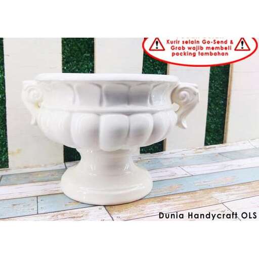 a white vase sitting on a tiled floor.
