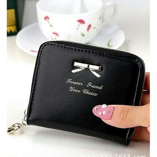 a handbag with a bow on it and a cup of coffee in the background.