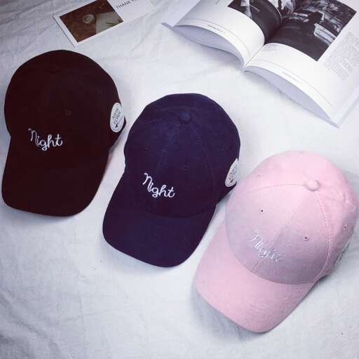 a pink hat and a book on a bed.