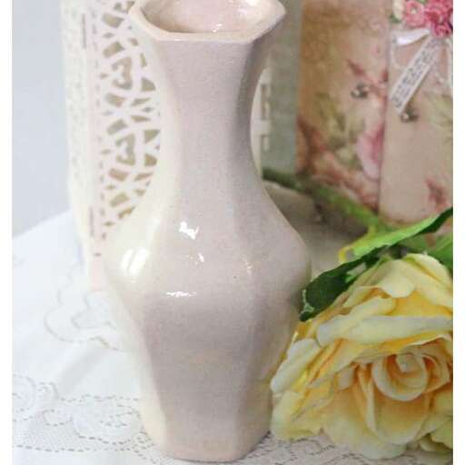 a white vase with a yellow rose in it.
