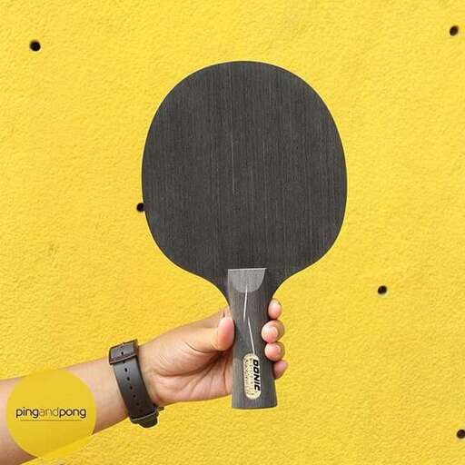 a hand holding a tennis racket with a yellow background.