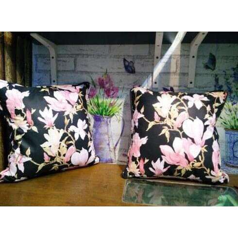 two pillows with flowers on them sitting on a table.