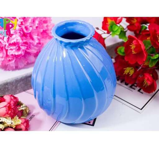 a blue vase sitting on top of a table next to flowers.