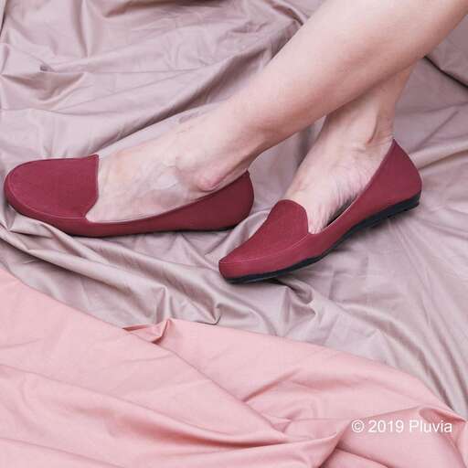 a woman's feet with a pair of shoes on a bed.