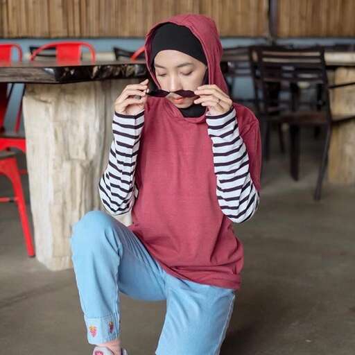 a woman in a red shirt and blue pants with a hoodie on her head.