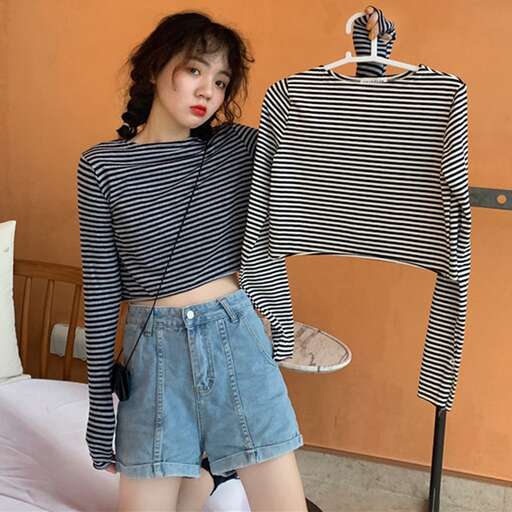 a woman wearing a striped shirt and denim shorts.