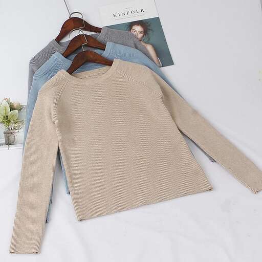 a sweater is laying on a bed with a book.