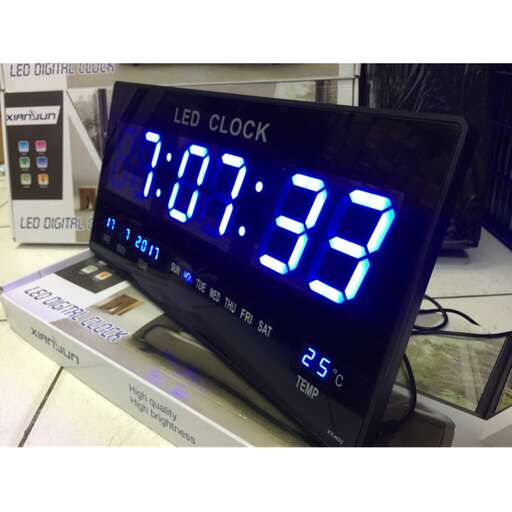a digital clock with the time displayed on a desk.