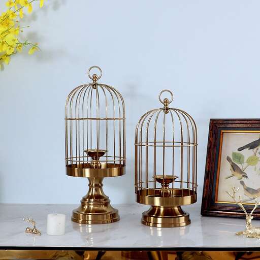 a table with two golden bird caged birds.