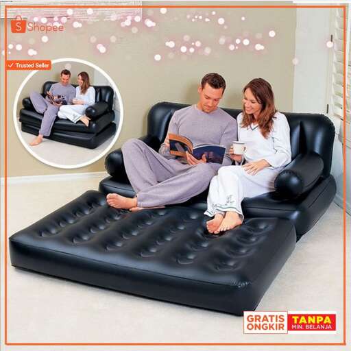 a couple sitting on a black leather couch.