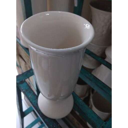a white vase sitting on a blue and green shelf.