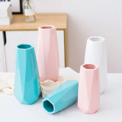 a white table with a pink vase on it.