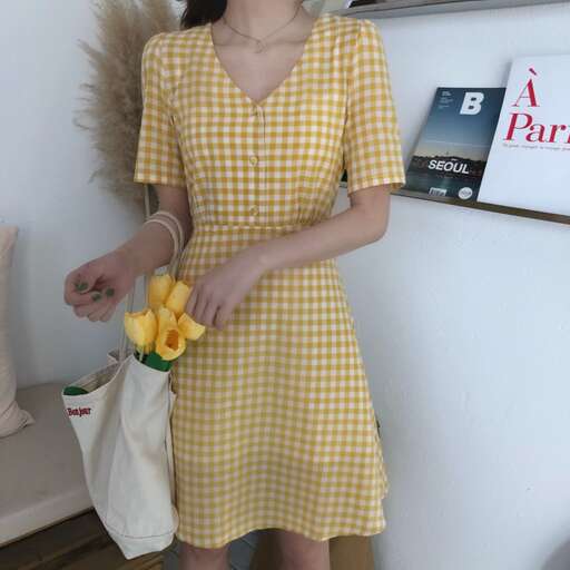 a woman in a yellow dress holding a bunch of bananas.