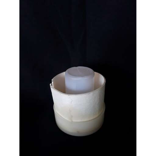 a small candle in a white glass vase