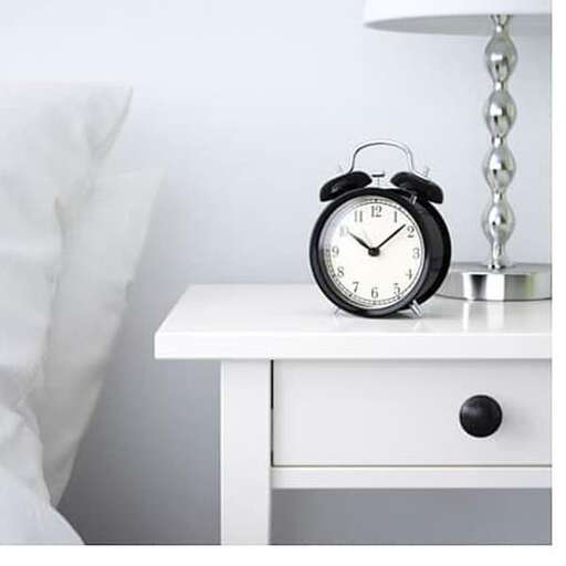 a white night stand with a clock on it.