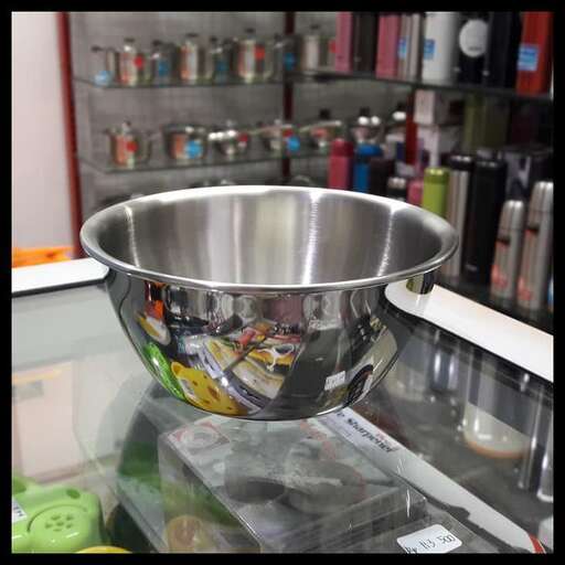 a silver bowl on a glass shelf in a store.