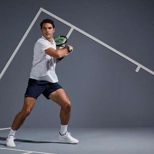 a man holding a tennis racket in front of a wall.