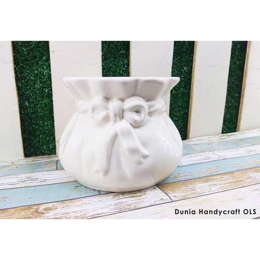 a white vase sitting on a wooden porch.