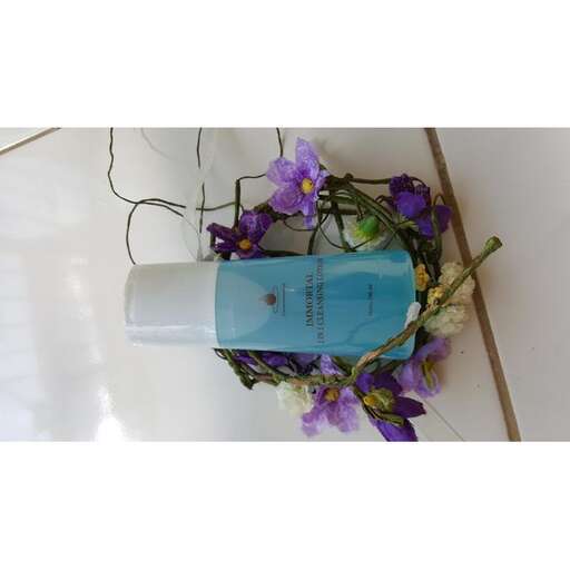 a blue bottle with flowers in it on a tile floor.