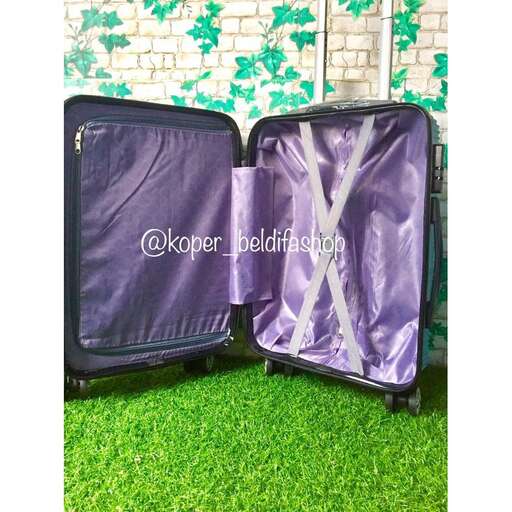 two suitcases sitting on the grass with a floral wall behind them.