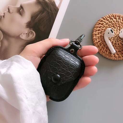a hand holding a small black car keychain.