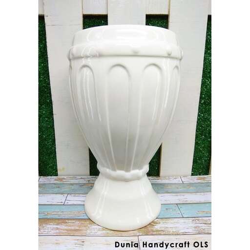 a white urn sitting on a wooden porch.