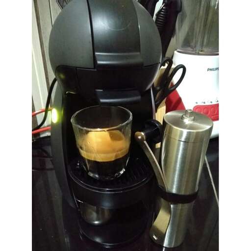 a coffee maker with a glass of coffee.