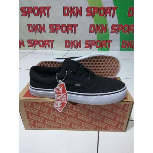 a pair of black sneakers with a red tag on the front.
