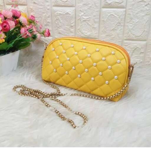 a yellow purse with a chain and a flower pot on the side.