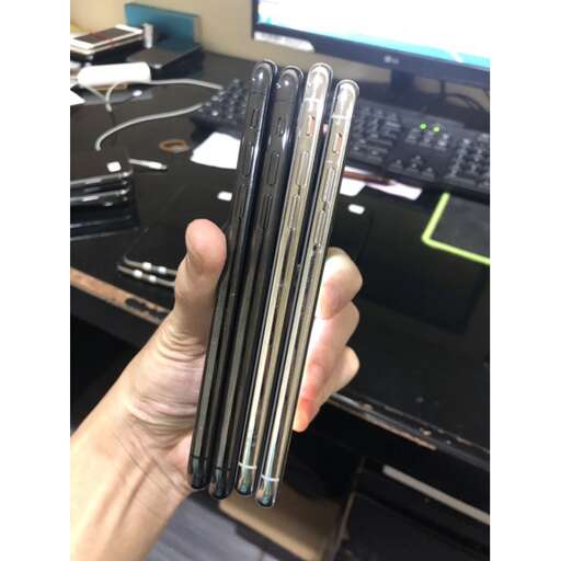 a hand holding a cell phone in front of a computer.