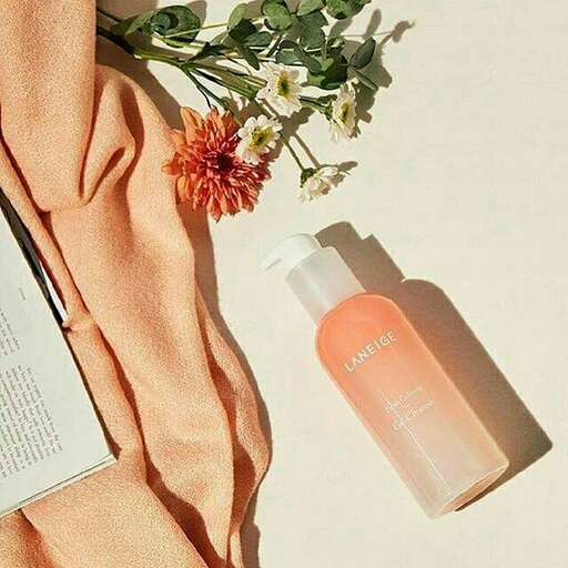 a bottle of liquid soap sitting on a blanket next to a flower.
