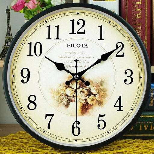 a clock with a flower on it sitting on a table.