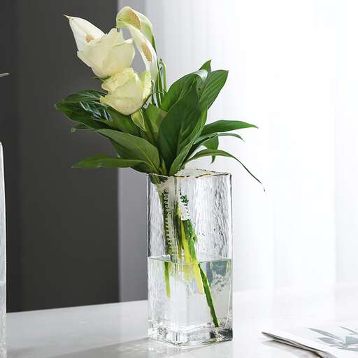 a vase filled with water and flowers sitting on a table.