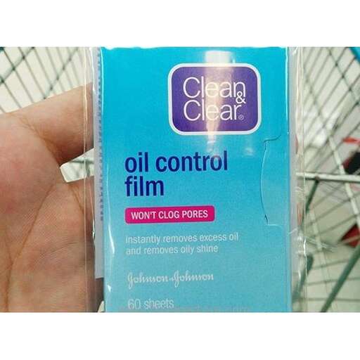 a hand holding a package of oil in a shopping cart.
