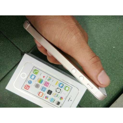 a hand holding a pen in front of a white cell phone.