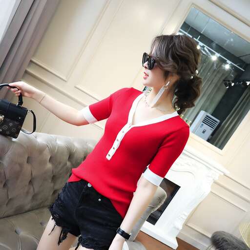 a woman in a red shirt and black shorts holding a purse.