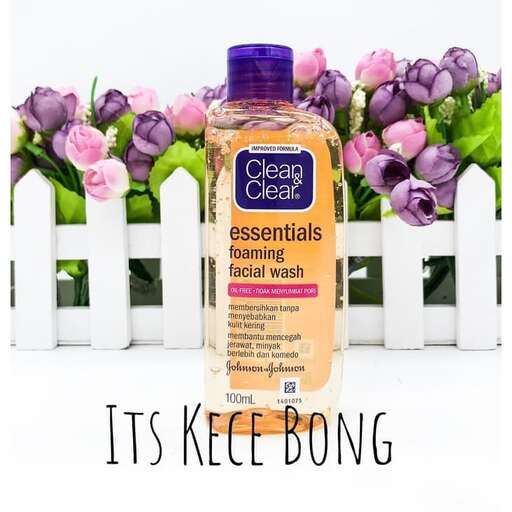 a bottle of soap with a bunch of purple flowers in the background.